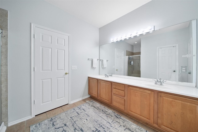 full bath featuring double vanity, a stall shower, a sink, tile patterned floors, and baseboards