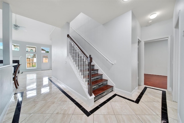 stairs with baseboards and ceiling fan