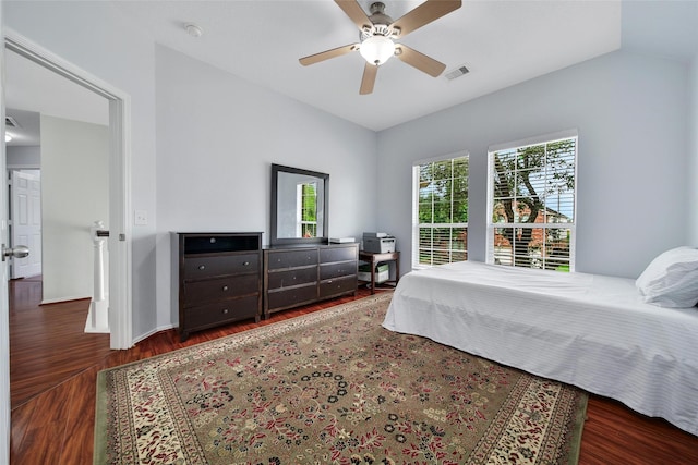 bedroom with ceiling fan, visible vents, vaulted ceiling, wood finished floors, and baseboards