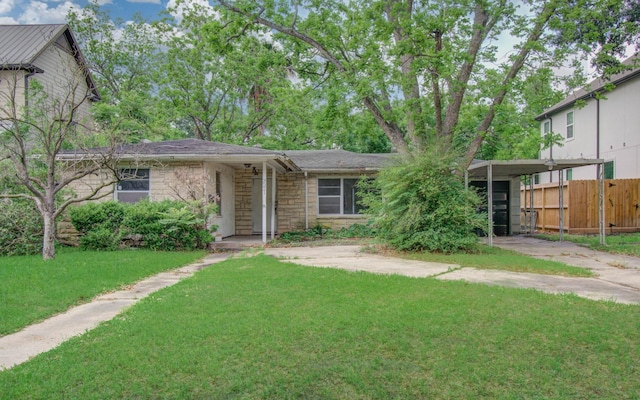 view of front facade featuring fence, a carport, stone siding, and a front lawn