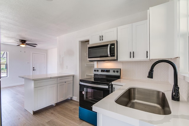 kitchen featuring a peninsula, white cabinetry, tasteful backsplash, a sink, and stainless steel appliances