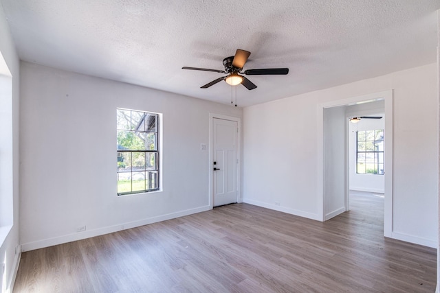unfurnished room with a textured ceiling, ceiling fan, and wood finished floors