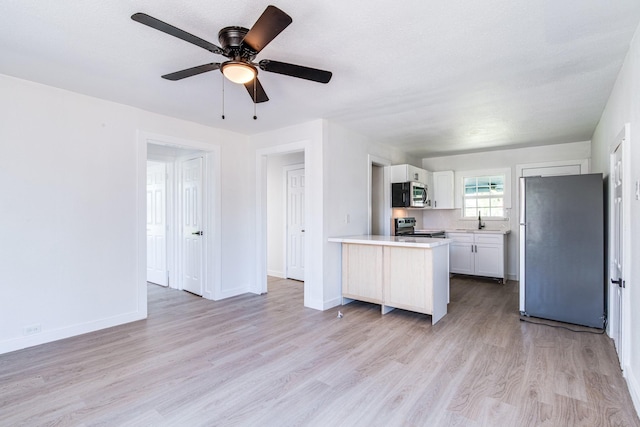 kitchen with light countertops, white cabinetry, a sink, light wood finished floors, and stainless steel appliances