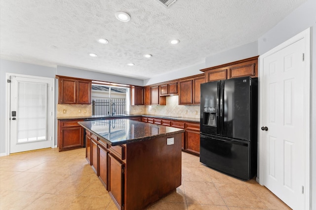 4103 Waterstone Dr, Missouri City, TX 77459 - kitchen with dark stone counters, a kitchen island, backsplash, and black refrigerator with ice dispenser
