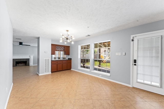 4103 Waterstone Dr, Missouri City, TX 77459 - unfurnished living room with a textured ceiling, visible vents, baseboards, a notable chandelier, and a premium fireplace