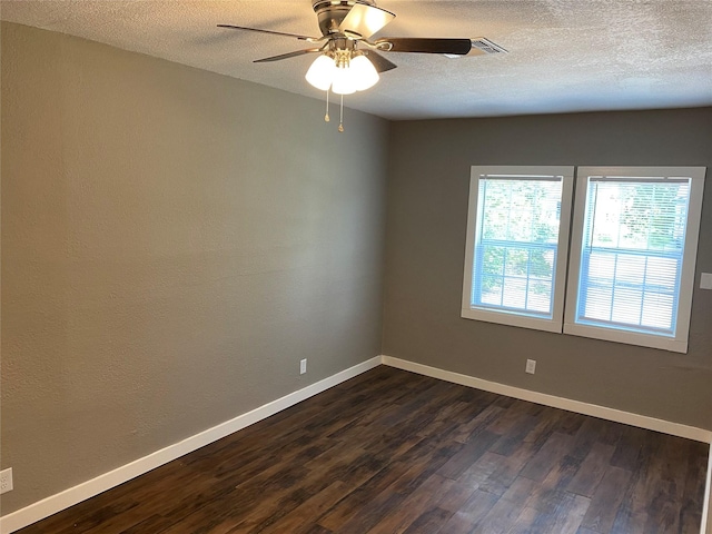 spare room with a textured ceiling, ceiling fan, baseboards, and dark wood-type flooring