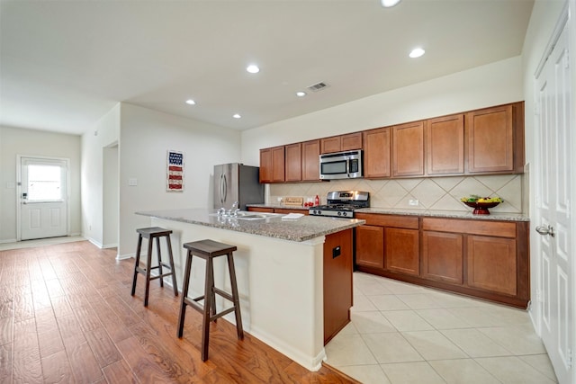 7908 Beryl Ct, Texas City, TX 77591 - kitchen featuring decorative backsplash, brown cabinetry, stainless steel appliances, and an island with sink