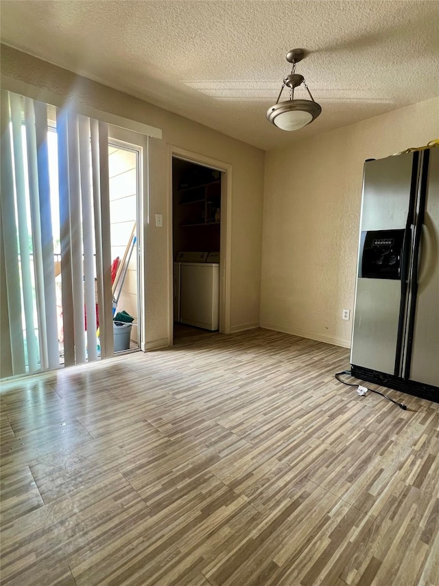 unfurnished living room featuring washer and dryer, a textured wall, a textured ceiling, baseboards, and wood finished floors