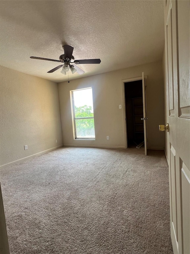 unfurnished room with carpet flooring, a ceiling fan, a textured ceiling, and baseboards