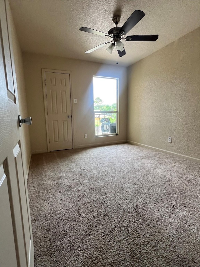 spare room featuring a textured wall, a textured ceiling, carpet, a ceiling fan, and baseboards