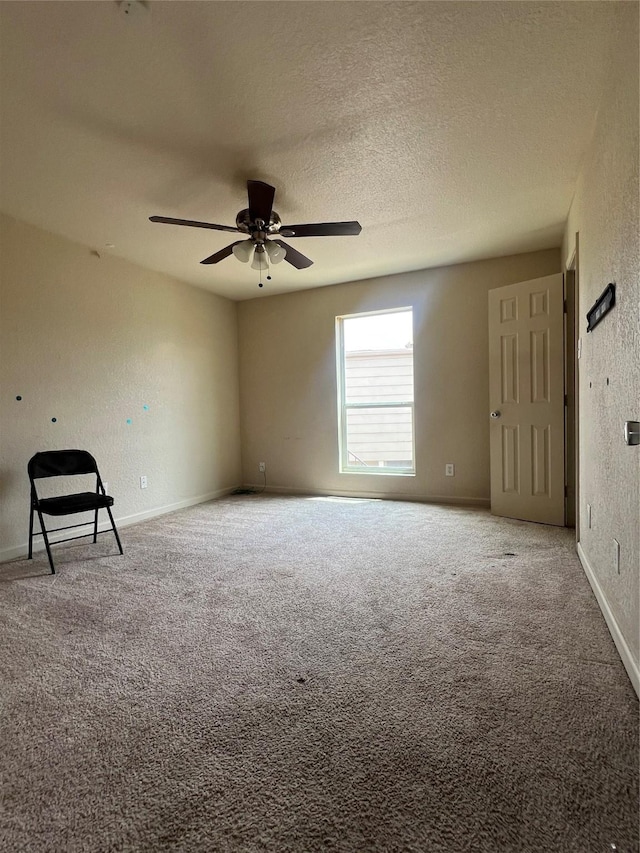 spare room with baseboards, carpet flooring, a textured wall, and ceiling fan