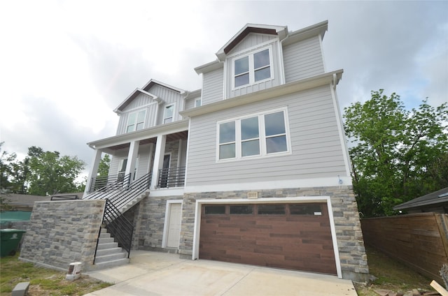craftsman-style home featuring a porch, stairway, concrete driveway, an attached garage, and stone siding