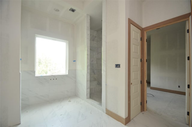 full bath with baseboards and a marble finish shower