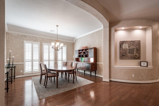 dining space with crown molding, wood finished floors, baseboards, arched walkways, and a notable chandelier