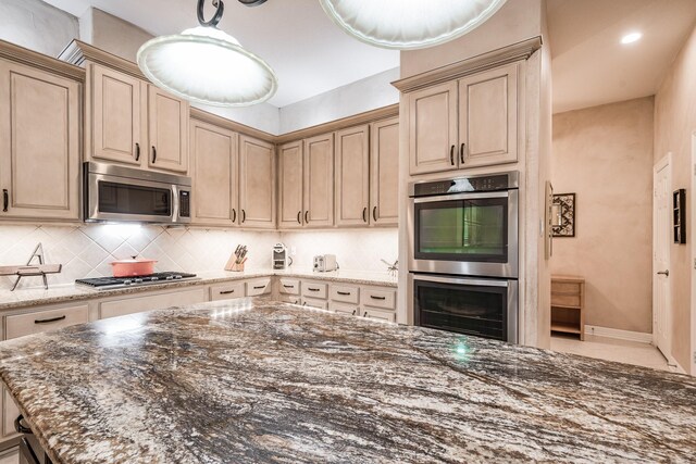 kitchen with appliances with stainless steel finishes, dark stone counters, baseboards, decorative backsplash, and pendant lighting