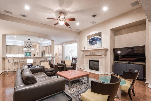 living room featuring ceiling fan, visible vents, wood finished floors, baseboards, and recessed lighting