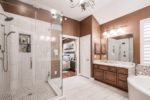 bathroom featuring an inviting chandelier, tile patterned flooring, vanity, a garden tub, and a stall shower