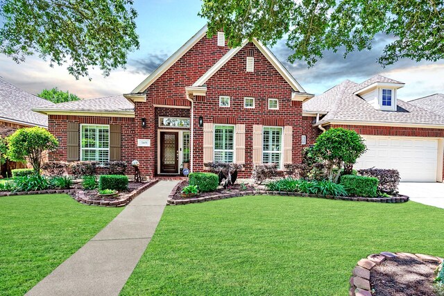 view of front of home with roof with shingles, a front lawn, brick siding, a garage, and driveway