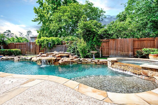 view of swimming pool with a fenced backyard and a pool with connected hot tub