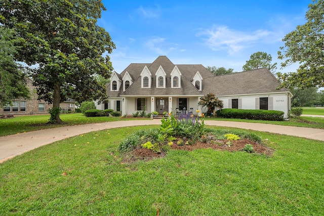 32743 Weybridge St, Fulshear, TX 77441 - cape cod house featuring a front yard, curved driveway, covered porch, and roof with shingles