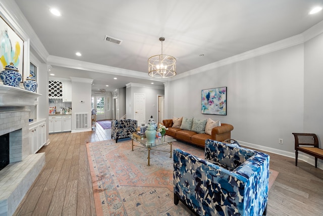32743 Weybridge St, Fulshear, TX 77441 - living room featuring a fireplace with raised hearth, light wood finished floors, a chandelier, recessed lighting, and crown molding