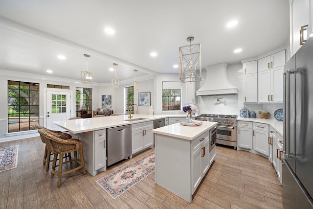 32743 Weybridge St, Fulshear, TX 77441 - kitchen featuring high end appliances, custom range hood, a peninsula, a kitchen island, and light countertops
