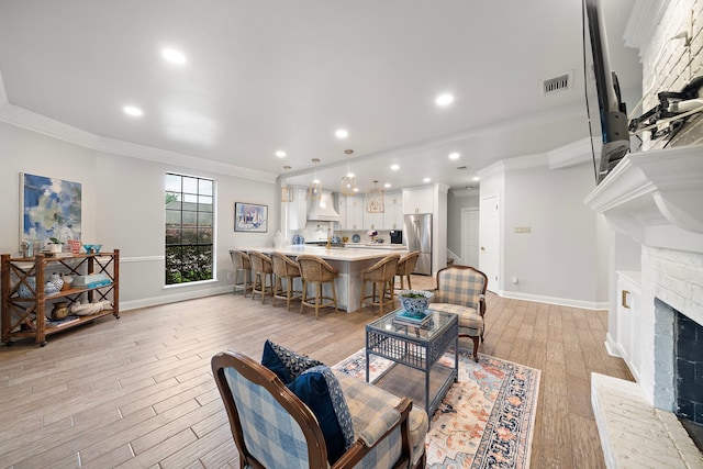 32743 Weybridge St, Fulshear, TX 77441 - living area with crown molding, light wood-style flooring, a brick fireplace, and recessed lighting