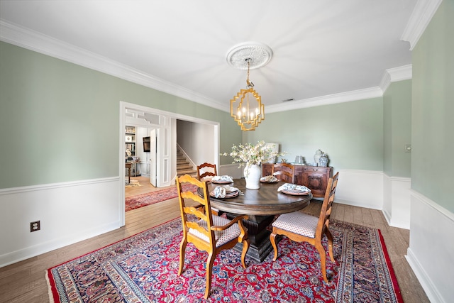 32743 Weybridge St, Fulshear, TX 77441 - dining space featuring a chandelier, crown molding, wood finished floors, stairs, and a wainscoted wall