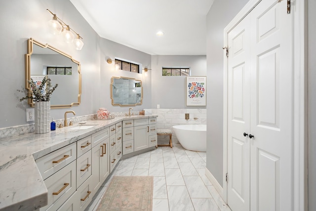 32743 Weybridge St, Fulshear, TX 77441 - bathroom with double vanity, a soaking tub, marble look tiles, and recessed lighting