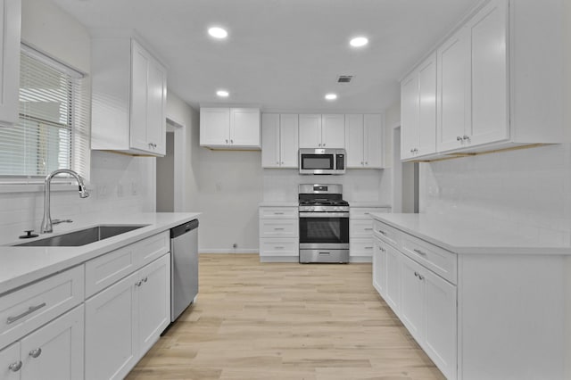 kitchen with light countertops, white cabinets, tasteful backsplash, a sink, and appliances with stainless steel finishes
