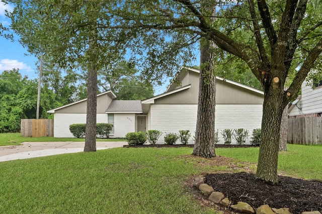 mid-century modern home with fence, a front lawn, and brick siding