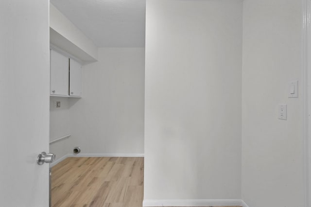 washroom featuring cabinet space, baseboards, and light wood-style floors