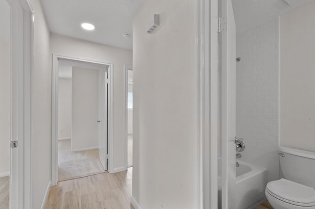 corridor with baseboards and light wood-type flooring