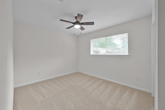 carpeted spare room with baseboards and a ceiling fan