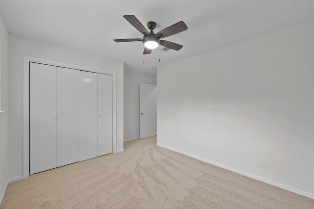 unfurnished bedroom with carpet flooring, baseboards, ceiling fan, and a closet