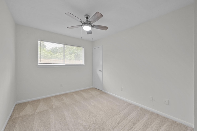 empty room featuring baseboards, ceiling fan, and light carpet