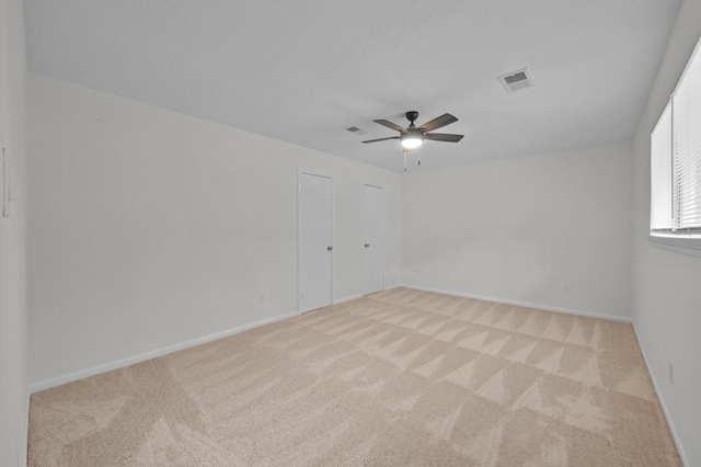 empty room with ceiling fan, visible vents, baseboards, and carpet