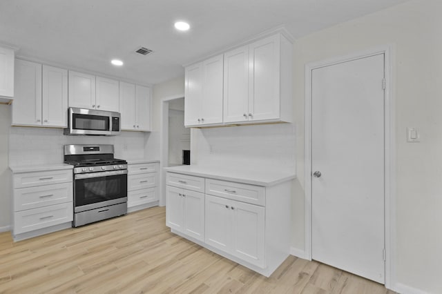 kitchen with visible vents, tasteful backsplash, light countertops, white cabinets, and stainless steel appliances