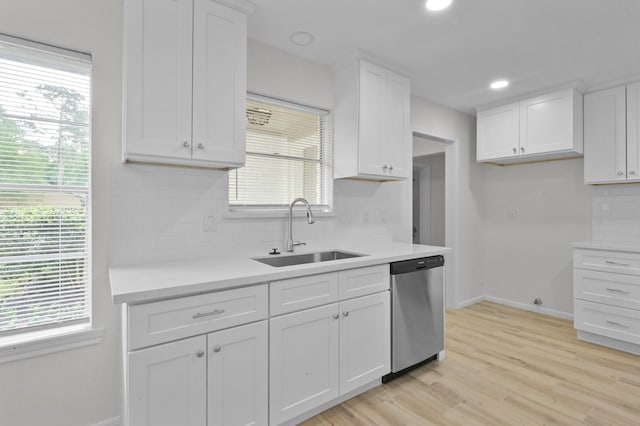 kitchen with a sink, baseboards, white cabinets, and dishwasher
