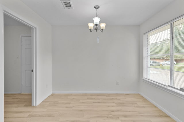 empty room with light wood-style floors, plenty of natural light, a chandelier, and visible vents
