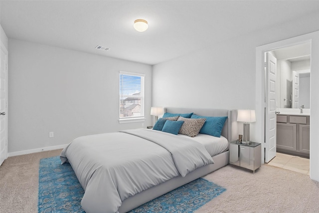 bedroom featuring light carpet, a sink, baseboards, ensuite bathroom, and visible vents