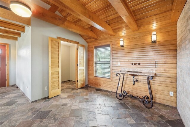 3139 Fm 1406, Winnie, TX 77665 - spare room featuring baseboards, stone tile floors, beam ceiling, and wood walls
