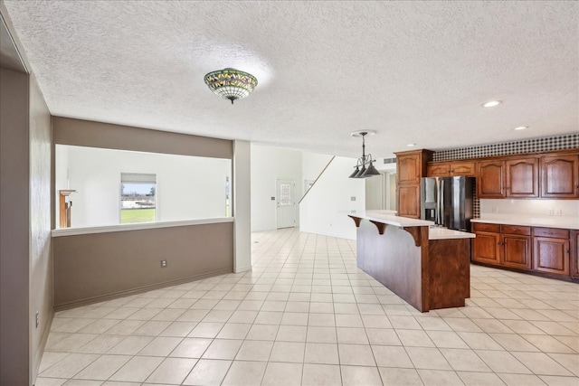 3139 Fm 1406, Winnie, TX 77665 - kitchen featuring brown cabinetry, a kitchen island, a kitchen breakfast bar, stainless steel refrigerator with ice dispenser, and light countertops