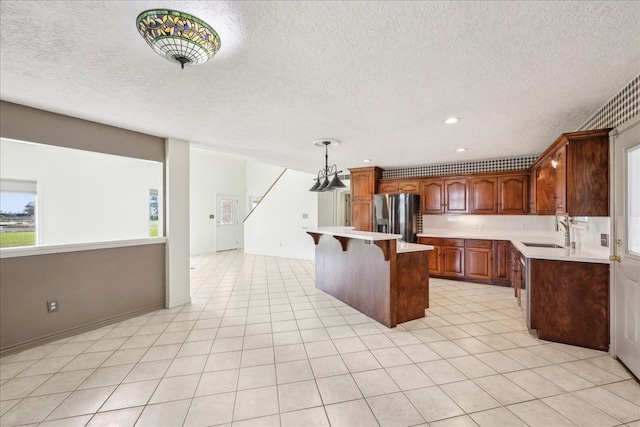 3139 Fm 1406, Winnie, TX 77665 - kitchen with stainless steel fridge, a sink, light countertops, a kitchen breakfast bar, and a textured ceiling