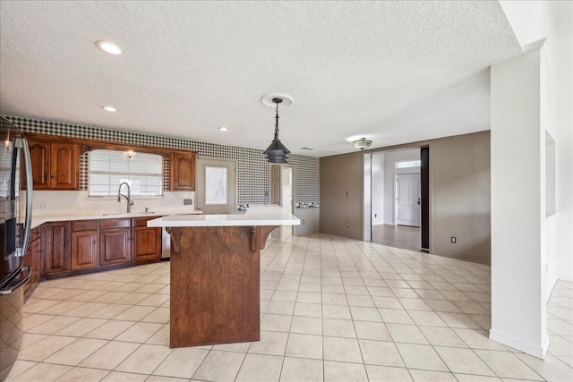 3139 Fm 1406, Winnie, TX 77665 - kitchen featuring a textured ceiling, a center island, a sink, light countertops, and a breakfast bar