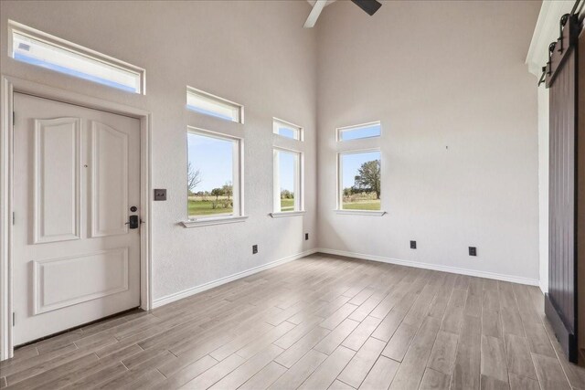 3139 Fm 1406, Winnie, TX 77665 - foyer featuring a ceiling fan, light wood-type flooring, a barn door, baseboards, and a high ceiling