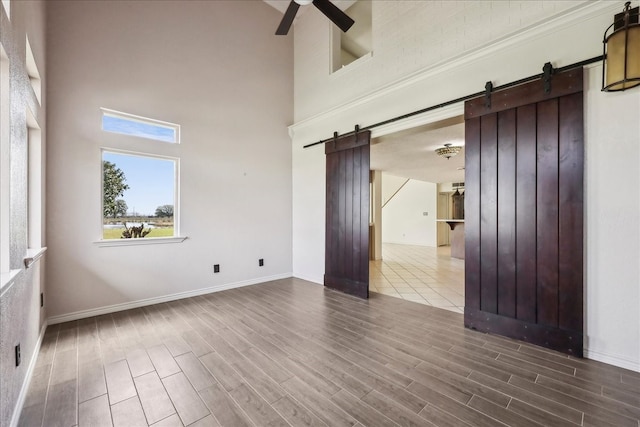 3139 Fm 1406, Winnie, TX 77665 - spare room featuring a ceiling fan, wood finish floors, a barn door, and a high ceiling