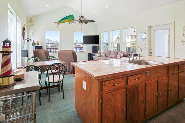 kitchen featuring a ceiling fan, lofted ceiling, tile counters, a sink, and carpet
