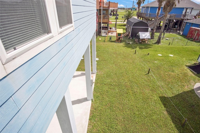 view of yard featuring a storage shed, fence, and an outbuilding