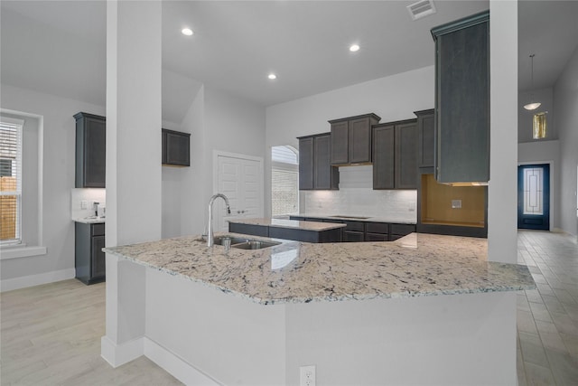 23415 Persimmon Creek Ln, Katy, TX 77493 - kitchen with backsplash, visible vents, a sink, light stone counters, and light wood-style flooring